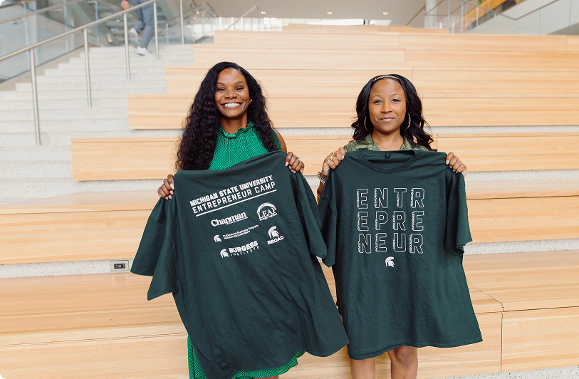 Two program participants holding entrepreneurship camp t-shirts