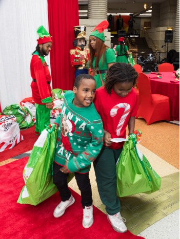 Two boys holding holiday gift bags