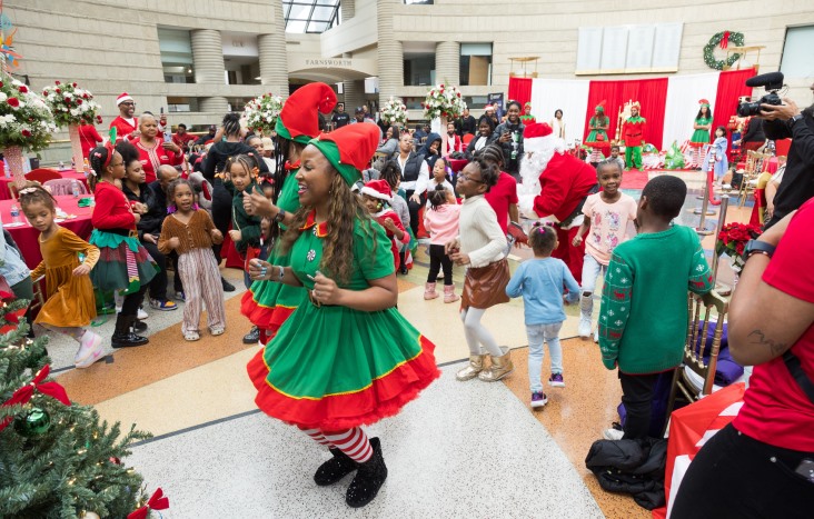 An elf dancing with children in the atrium