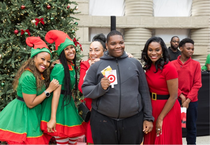 Guests posing with two elves and a gift card